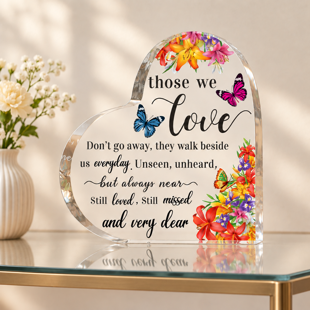 Heart-shaped acrylic memorial keepsake plaque on a glass table with flowers in the background; table and flowers not included