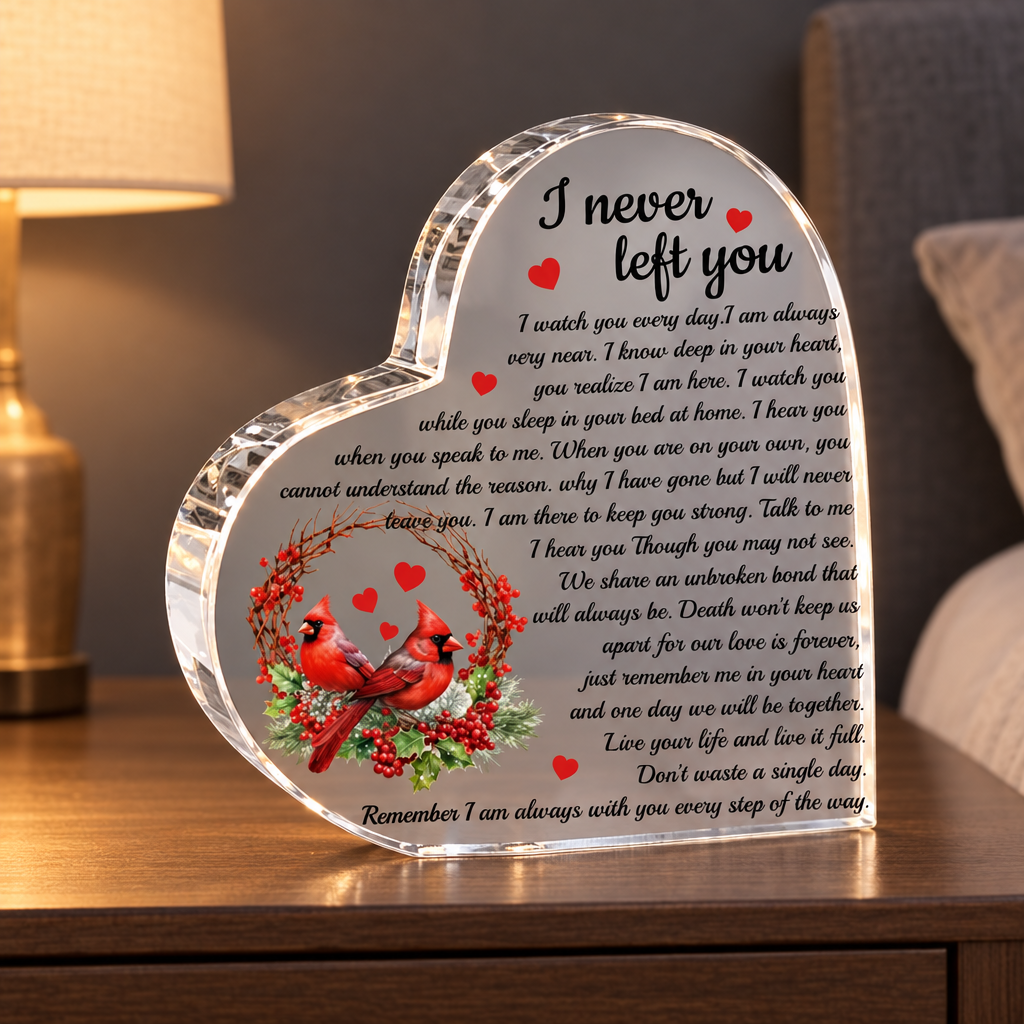 Heart-shaped acrylic cardinal memorial plaque on a nightstand beside a softly glowing lamp; furniture and lamp not included
