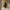 Golden Mosaic Cremation Urn on a stone pedestal with a long yellow linen runner hanging on the wall behind it